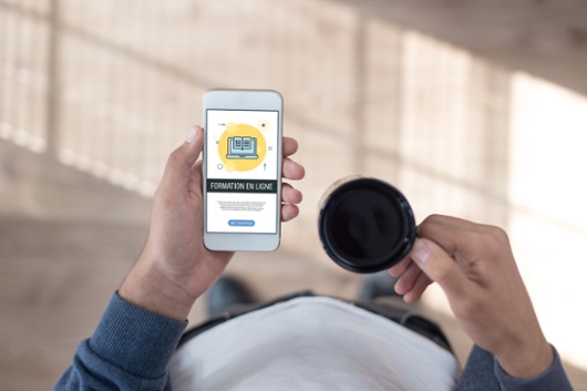 Personne tenant un téléphone et une tasse à café