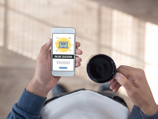 Person holding cell phone and coffee mug