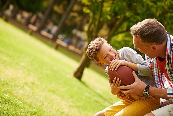 Boy playing football with father figure